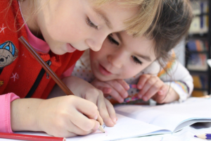 Children at a table working in a schoolbook - Schools and other buildings where people spend a lot of time should have radon inspection to ensure safety