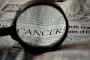 magnifying glass look at article about cancer in newspaper - radon and blood cancer link discussed by radon-rid